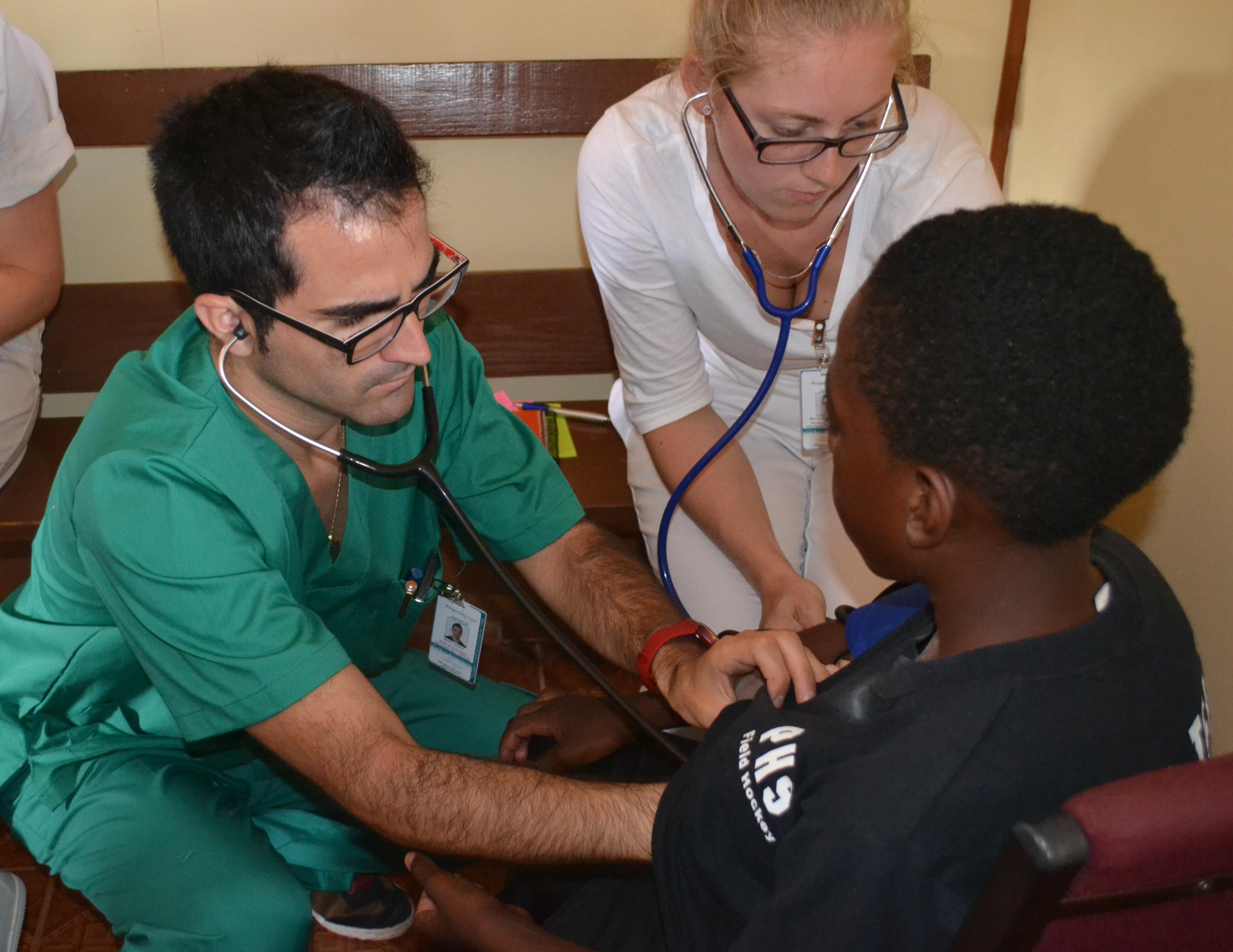 Durante sus prácticas médicas en Jamaica, dos internos realizando una revisión. Internos de medicina examinando a un niño en Jamaica.
